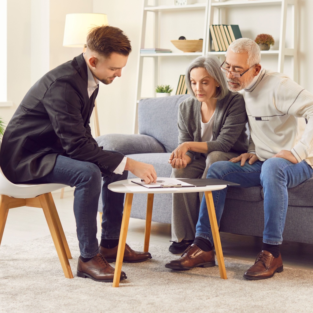 Couple sitting with a financial adviser and looking at paperwork