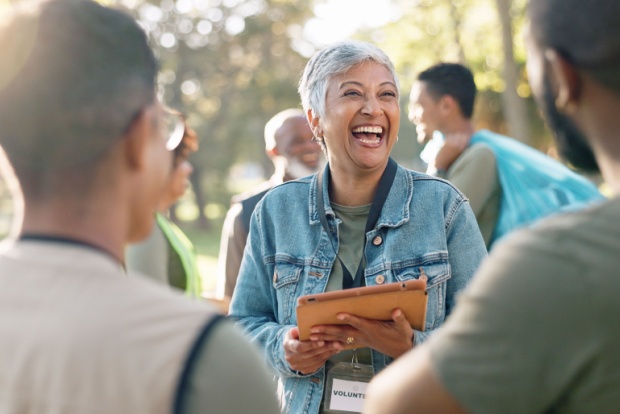 A woman with a clipboard volunteering at an event in a park.