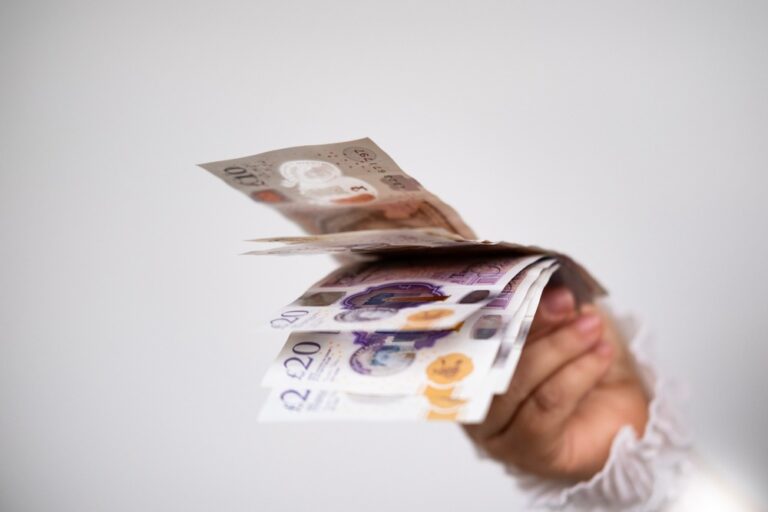 A hand holding UK bank notes